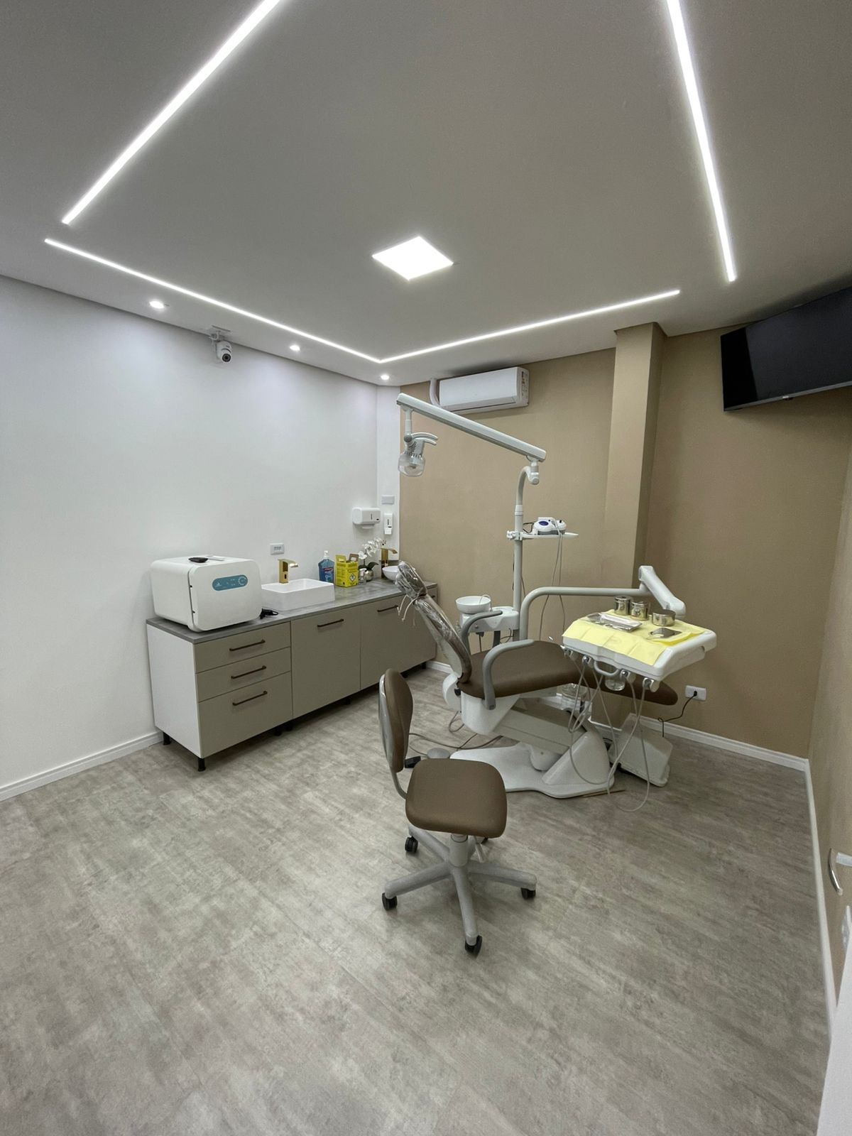 Consultório da clínica com cadeira odontológica e iluminação moderna